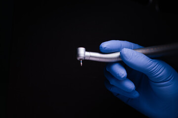 a dental tip and a metal bur in dentistry treats caries a blue gloved hand holds