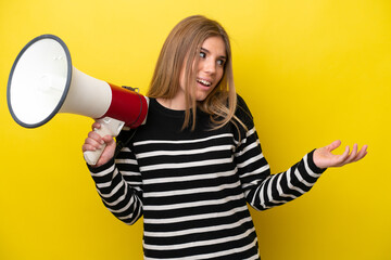 Young caucasian woman isolated on yellow background holding a megaphone and with surprise facial expression
