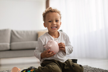 African American Little Boy Holding Piggybank With Personal Savings Indoor