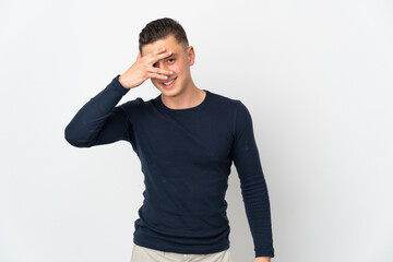 Young caucasian man isolated on white background covering eyes by hands and smiling