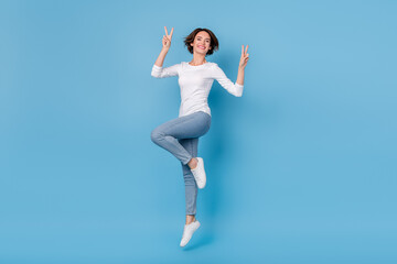 Fototapeta na wymiar Full size photo of excited crazy positive girl jumping up fooling around show v-sign isolated on blue color background
