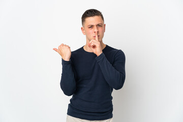 Fototapeta premium Young caucasian man isolated on white background pointing to the side and doing silence gesture