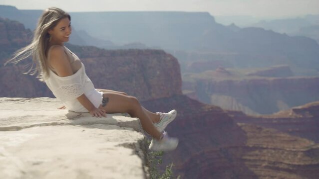 A young woman looking to Horseshoe Bend and Colorado river from the edge of 1000ft canyon in Glen Canyon National Recreation Area, Arizona, USA