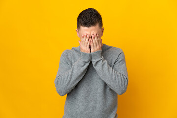 Young caucasian man isolated on yellow background with tired and sick expression