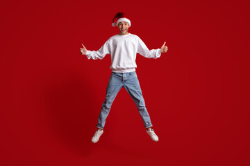 Christmas Offer. Excited Guy In Santa Hat Jumping And Gesturing Thumbs Up