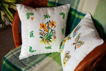 Two pillows with embroidery in the shape of flowers and butterflies.