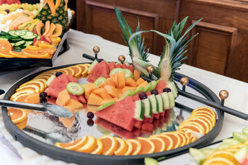 Watermelon, kiwi, mango, and orange slices make up a decorative display on the buffet table for the party guests to eat