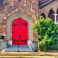 Vintage red entrance door and brick wall of an old church. Gorgeous architectural design of the...