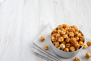 Homemade Caramel Popcorn in a gray Bowl on a white wooden background, side view.  Copy space.
