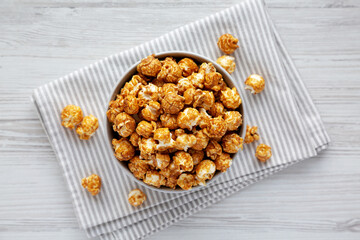 Homemade Caramel Popcorn in a gray Bowl on a white wooden table, top view. Flat lay, overhead, from above.