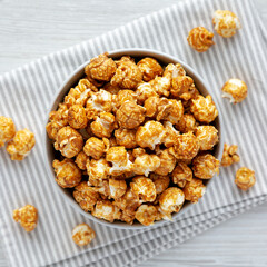 Homemade Caramel Popcorn in a gray Bowl on a white wooden background, top view. Flat lay, overhead, from above.