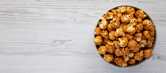 Homemade Caramel Popcorn in a gray Bowl on a white wooden background, top view. Flat lay, overhead, from above. Copy space.