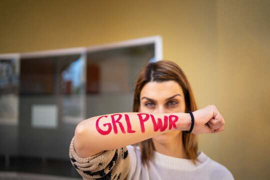 A young woman showing the letters "GLR PWR" written on her arm.