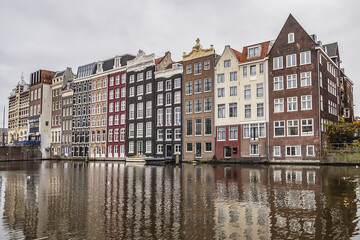 Fototapeta na wymiar Damrak Waterfront: Typical old Dutch houses at Damrak water canal. Amsterdam, Netherlands.