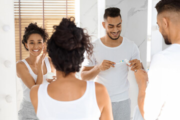 Morning Rituals. Young Middle Eastern Couple Getting Ready Near Mirror In Bathroom