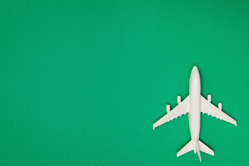 Airplane model. White plane on green background. Travel vacation concept. Summer background. Flat lay, top view, copy space.