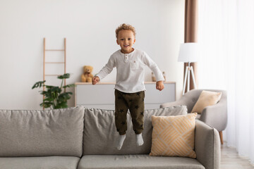 Cheerful African American Little Boy Jumping Having Fun At Home