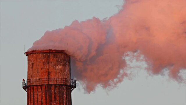 Big factory chimney polluting the atmosphere in sunset light. Thermal power plant chimney shell.