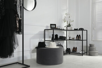Shelving unit with stylish women's shoes, clothes and accessories in dressing room