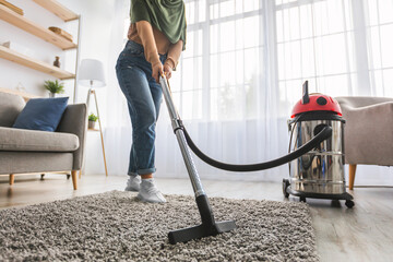 Closeup of muslim woman cleaning rug carpet with vacuum cleaner