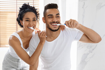 Morning Routine. Smiling Young Middle Eastern Couple Brushing Teeth In Bathroom Together