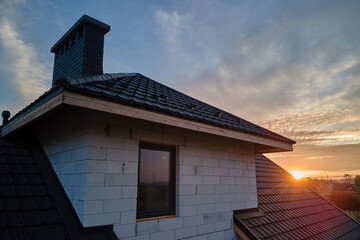 Unfinished house with aerated lightweight concrete walls and wooden roof frame covered with metallic tiles under construction