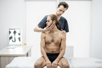 Physical therapist does manual therapy to a young athletic guy at medical office. Concept of manual...