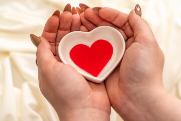 Obraz premium hands hold a red heart on white background