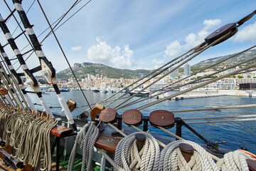 A view from an old sailing ship, many ropes hanging down from above, blue sky in the background on...