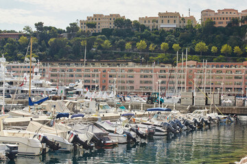 Fototapeta na wymiar Monaco, Monte-Carlo, a lot of small motor boats are parked side by side in the port, with fenders between them to avoid collision at sunny day, mooring ropes go into the azure water