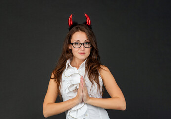 Innocent devil. Woman in Halloween costume. Satanic girl make prayer hands. Halloween party