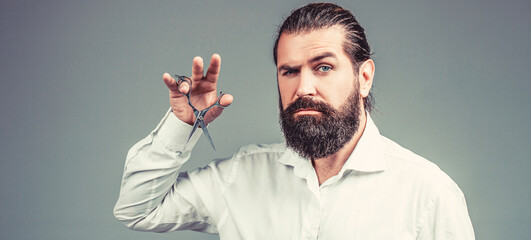 Barber scissors. Vintage barbershop, shaving. Male in barbershop, haircut, shaving. Bearded man isolated on gray background. Mans haircut in barber shop. Barber scissors, barber shop