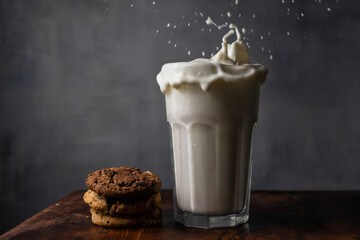 Splashing milk in a glass with chocolate chip cookies