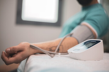 Doctor taking blood pressure and pulse on the arm of a patient in the clinic