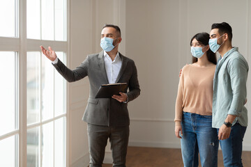 Estate Agent In Facemask Showing Buyers New Apartment
