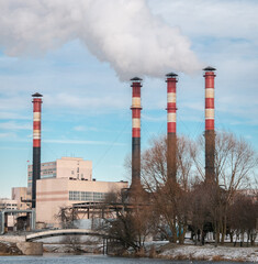Factory chimneys release clouds of smoke into the sky against a blue sky. The concept of air pollution, environment, industry and ecology, global warming.