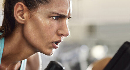 Disciplined and determined. Cropped shot of a determined looking young woman working out on an...