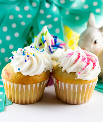 A close up view of assorted mini cupcakes with Easter basket in background.