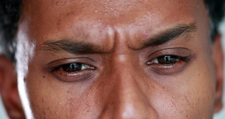Worried african man closeup eyes squinting, concerned preoccupied black guy macro close-up