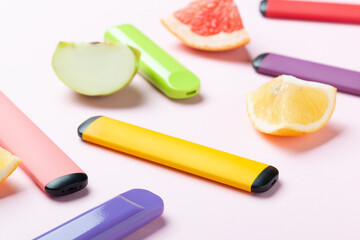 Electronic cigarettes with different fruit flavors with ingredients on colored backgrounds