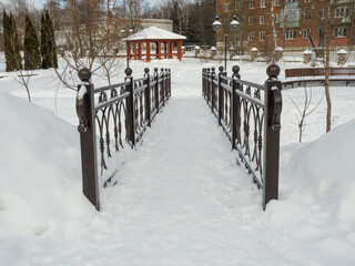 forged bridge over the river in the city park in winter