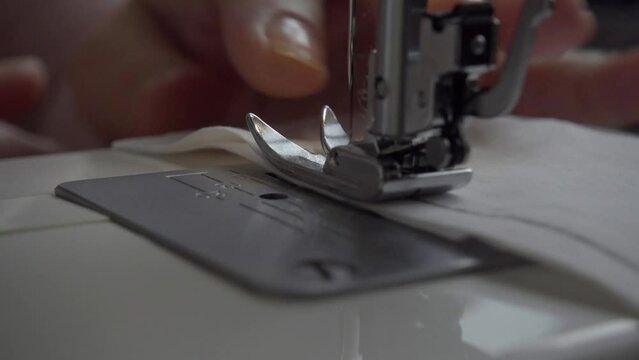 The needle of a sewing machine makes a thread stitch.