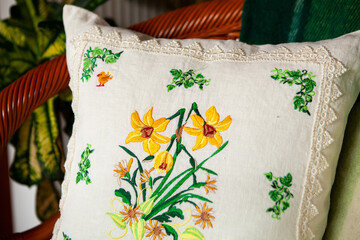 Decorative pillow in white with embroidery in the form of flowers.