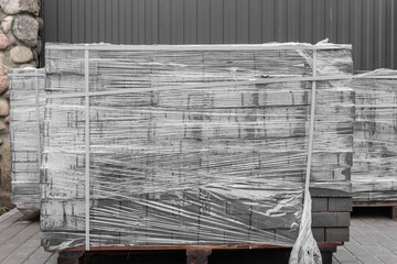 Stone pavement blocks in a pile of tiles building material packed in polyethylene film on...