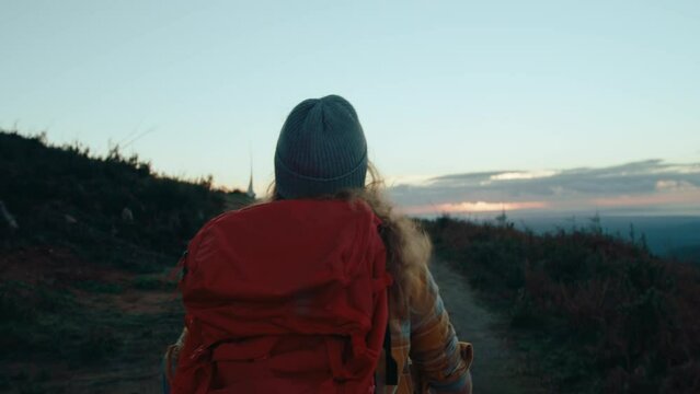 Handheld authentic shot of young woman hike on top of mountain with red backpack. Cinematic adventure movie. Female explorer, independent woman see the world. Hiker climb to top, backpacker on a trip