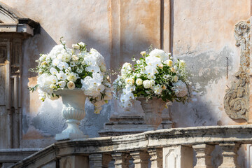 Fototapeta na wymiar Romantischer Hochzeitsstrauß in einer barocken Steinvase vor der Chiesa di San Giuseppe in Taormina in Italien