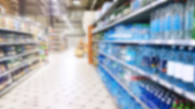 Abstract blur image of supermarket background. Defocused shelves with water bottles, food. Grocery shopping. Store. Retail industry. Rack. Discount price. Inflation and economic crisis concept. Aisle.