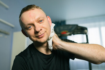 Tired man wiping sweat after exercising on treadmill at home. Cardio Run Workout
