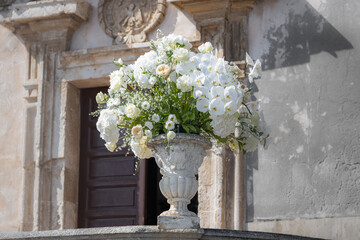 Romantischer Hochzeitsstrauß in einer barocken Steinvase vor der Chiesa di San Giuseppe in...