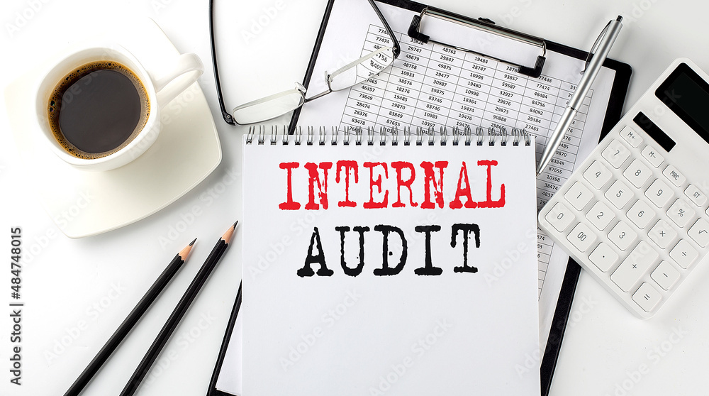 Poster internal audit text on the paper with calculator, notepad, coffee ,pen with graph